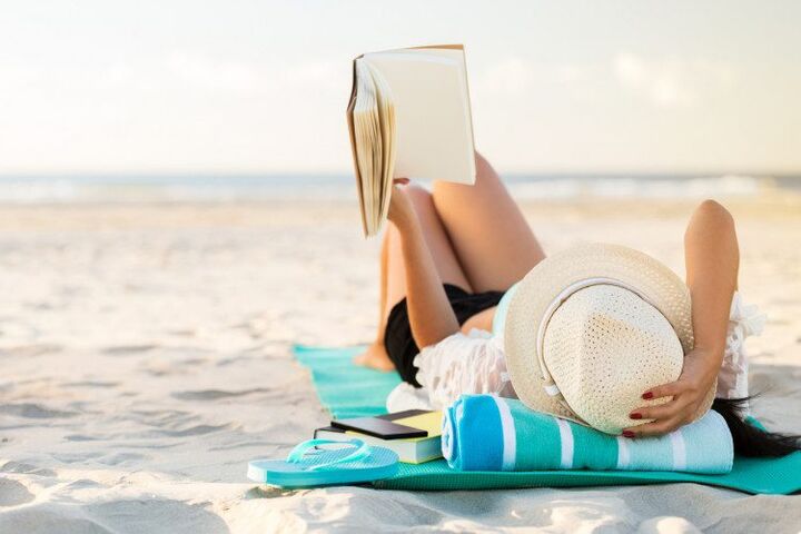 vrouw leest in haar eentje boek op het strand